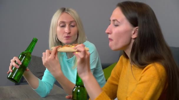 Mutfaktaki en mutlu iki kız arkadaş pizza yiyor ve bira içiyor.. — Stok video