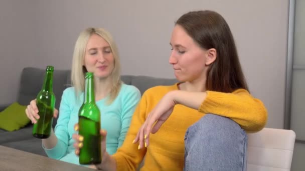 Dos chicas, bebiendo cerveza y comiendo deliciosa pizza, en casa en su cocina. — Vídeo de stock