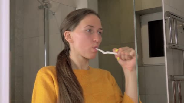 Žena se odráží v zrcadlovém kartáči zuby zubním kartáčkem a zubní pastou — Stock video