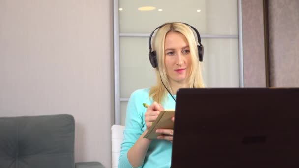 Freelancer femenina con auriculares está hablando en el chat de vídeo con el ordenador portátil. — Vídeos de Stock