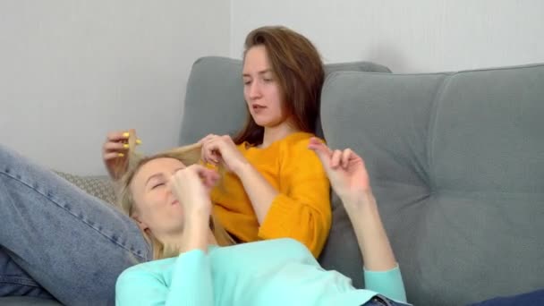 Charmante europäische Frauen, die auf der Couch liegen, albern herum und lachen. — Stockvideo