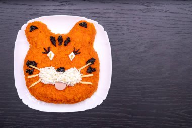 Havuç, yumurta, salatalık, patates, kuru erik ve sosisten yapılmış 2022 kaplan sembolü şeklinde komik bir salata. Yılbaşı yemeklerinin fotokopi odası. Tatil, yemek sanatı