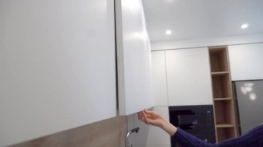 Mutfak dolabında bir kadın çekmece açıyor. Kapat..