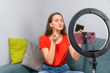 Genç, neşeli, güzel, koyu renk saçlı kadın kozmetik hakkında bir video kaydediyor ya da cep telefonu kamerasında bir güzel akışı yönetiyor.