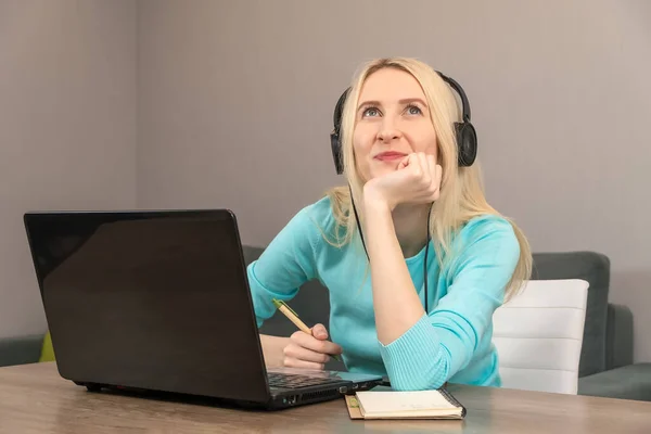 Młoda Blondynka Turkusowej Kurtce Pięknym Uśmiechem Słuchawkach Siedzi Przy Laptopie — Zdjęcie stockowe