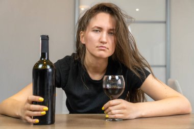 Depresyondaki saçları dağınık, üzgün duyguları olan, ilgisiz, masada içki içen güzel, siyah saçlı bir kadın.