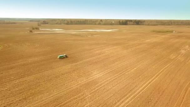 En röd gammal traktor gödslar ett grönt fält på våren — Stockvideo