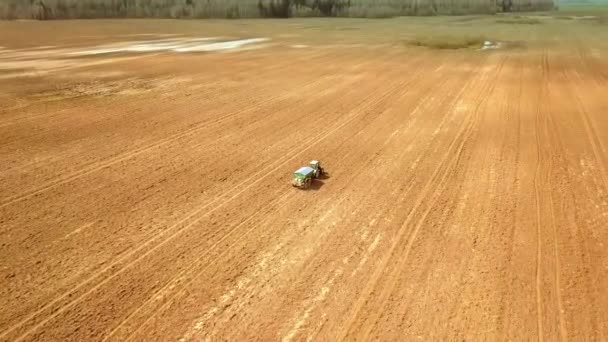 Um trator velho vermelho fertiliza um campo verde na primavera — Vídeo de Stock