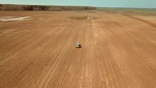 Flygfoto över en jordbrukstraktor som besprutar ett fält med gödselmedel. — Stockvideo