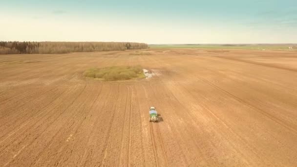 Un vieux tracteur rouge fertilise un champ vert au printemps — Video