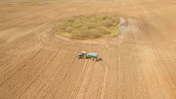 Ilmakuva maataloustraktorista, joka ruiskuttaa pellolle lannoitetta. — kuvapankkivideo