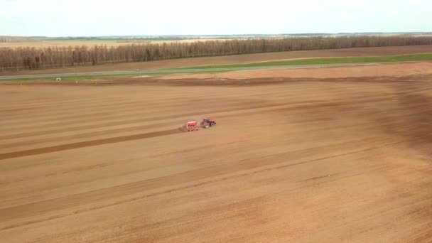 Skyting fra drone som flyr over traktor med harrow-system, – stockvideo