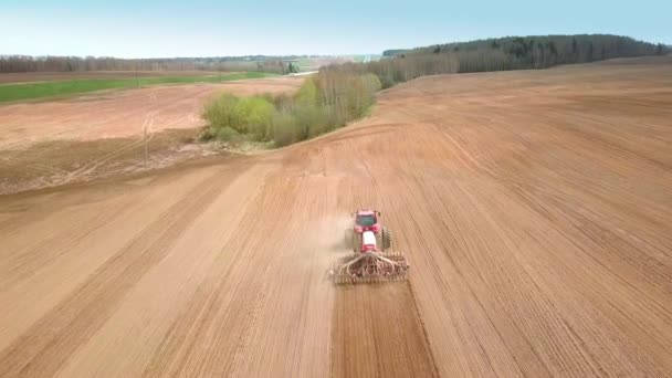 Skyting fra drone som flyr over traktor med harrow-system, – stockvideo