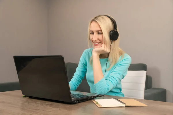 Młoda Blondynka Siedząca Przy Biurku Dużych Słuchawkach Laptopie Słuchająca Wykładu — Zdjęcie stockowe