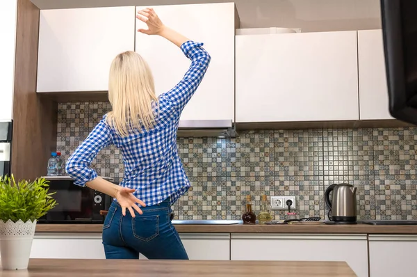 Wesoła Młoda Szczupła Blondynka Niebieskich Dżinsach Koszuli Gotuje Kuchni Tańczy — Zdjęcie stockowe