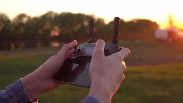 Las manos de una mujer sostienen un control remoto para un dron al atardecer. — Vídeo de stock