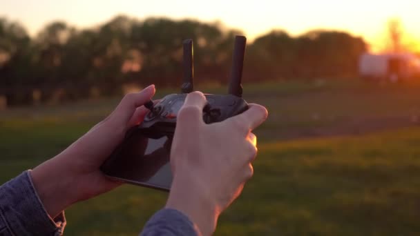 Las manos de una mujer sostienen un control remoto para un dron al atardecer. — Vídeo de stock