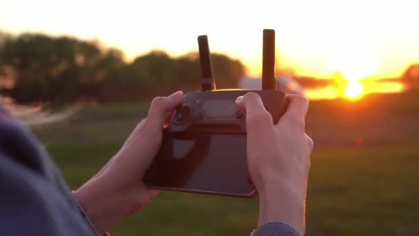 Les mains d'une femme tiennent une télécommande pour un drone au coucher du soleil gros plan. — Video