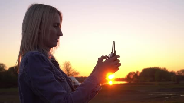 As mãos de uma mulher seguram um controle remoto para um drone ao pôr-do-sol de perto. — Vídeo de Stock