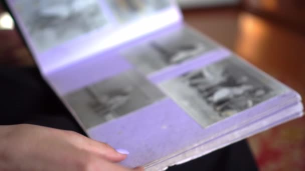 Junge Frau blättert in Familienalbum mit alten Schwarz-Weiß-Fotos — Stockvideo