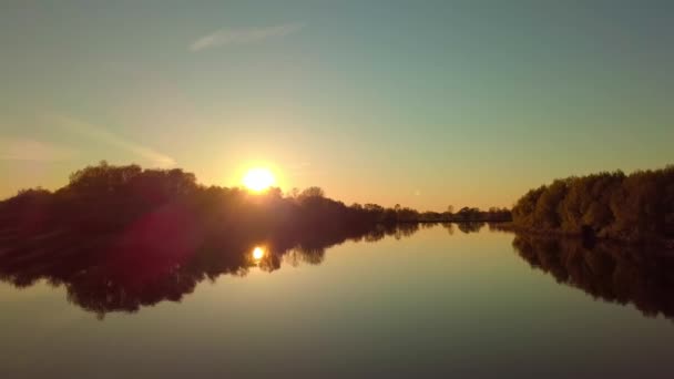 De drone vliegt over een prachtig zomerlandschap met een rivier bij zonsondergang. — Stockvideo