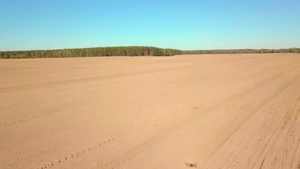 El dron vuela sobre un campo arado. La sombra de ella es visible en el suelo. — Vídeo de stock