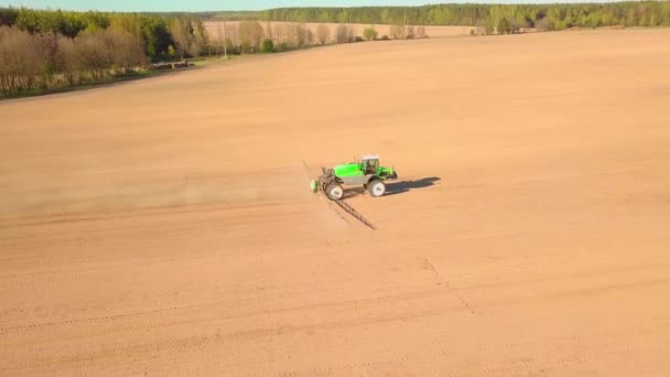 Traktor som sprayer et jorde med sprøytevæske, ugressmidler og plantevernmidler ved solnedgang. – stockvideo