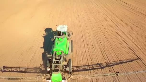 Traktori ruiskuttaa pellolle ruiskua, rikkakasvien torjunta-aineita ja torjunta-aineita auringonlaskun aikaan. — kuvapankkivideo