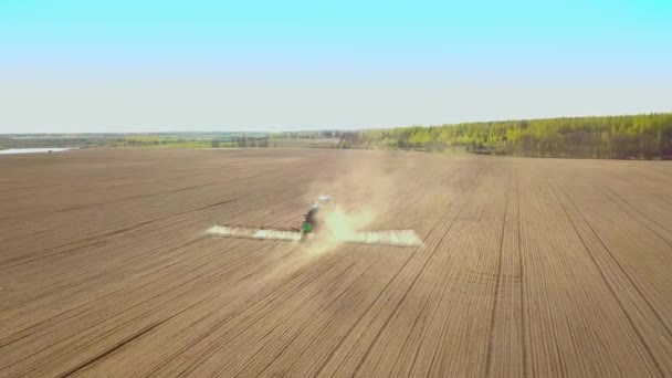 Traktor besprutning av ett fält med spruta, herbicider och bekämpningsmedel vid solnedgången. — Stockvideo