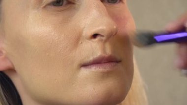 Güzellik salonundaki bir müşteri makyaj yapar. Yüze temel uygular.