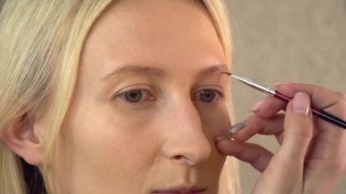 Güzellik salonundaki bir müşteri makyaj yapar. Makyöz kaşını çizer.