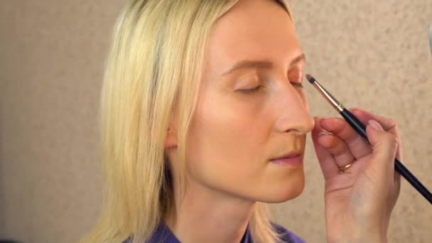 Stylist-make-up artist master brengt oogschaduw aan op een jong model — Stockvideo