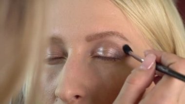 Güzellik salonundaki bir müşteri makyaj yapar. Makyaj sanatçısı göz farı yapar