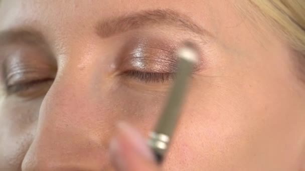 Stilistisk sminkør mester bruker øyenskygge på en ung modell – stockvideo