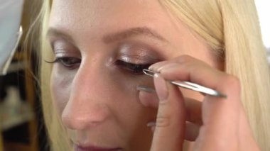 Profesyonel makyöz yapıştırıcıya takma kirpik yapıştırmak için cımbız kullanır.