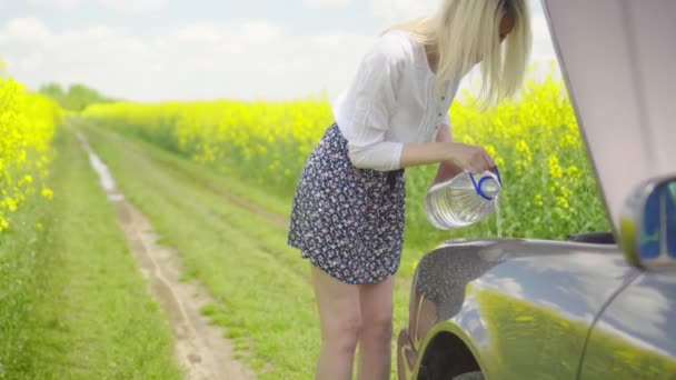 Молодая блондинка в рубашке и юбке льет жидкость для стеклоочистителя в машину — стоковое видео