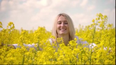 Mutlu genç bir çiftçi kadın kolza tohumu çiçeklerini sevgiyle kucaklıyor..