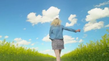 Genç bir kadın çiçek açan bir ırz tohumunun arasında koşuyor..