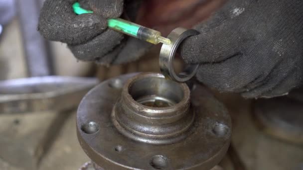 Master's hands lubricate the bearing cage with oil, and press it into the hub. — Stock Video