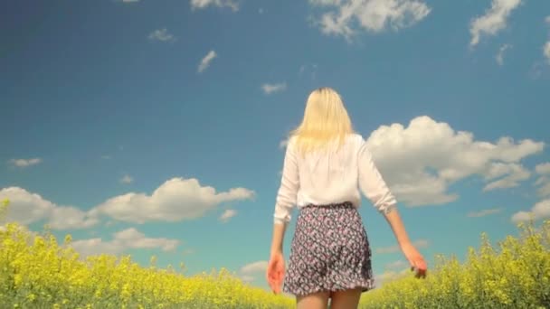 A young woman runs through a field of flowering rapeseed. — Stock Video