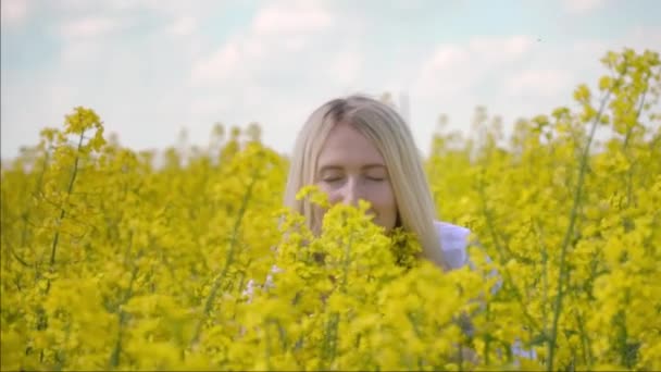 En glad ung bonde kvinna omfamnar kärleksfullt hennes rapsfrö gröda blommor. — Stockvideo