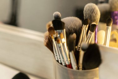 Makyaj sanatçısının masasında birçok farklı makyaj fırçası duruyor. Yuvarlak bir kavanozda, yakın plan, seçici odaklı.