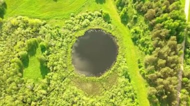 Yukardan, mükemmel yuvarlak şekilli küçük bir gölün üzerinden uçuyor..