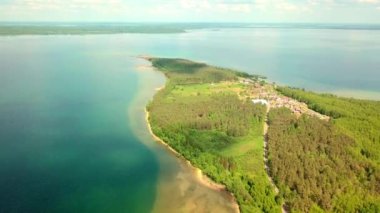 İnsansız hava aracı, yeşil bitki örtüsü ve yarımadanın arka planında, gölün üzerinde uçuyor..