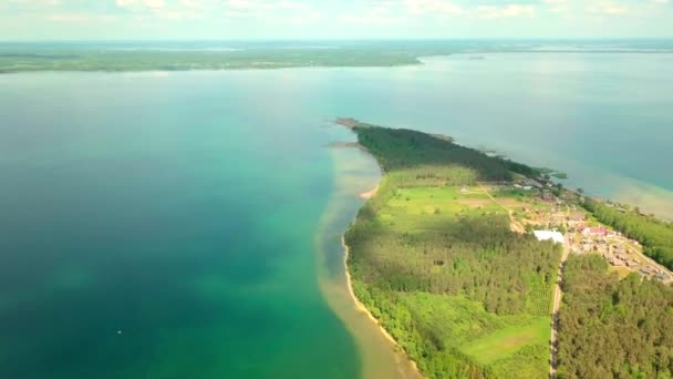 Dron lata nad jeziorem na tle półwyspu i zielonej roślinności. — Wideo stockowe