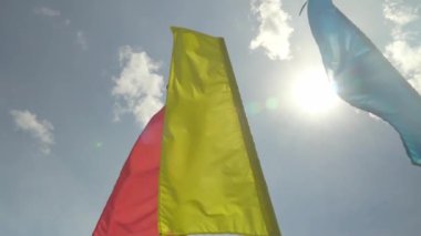 Mavi gökyüzüne karşı rüzgarda dalgalanan renkli tatil bayrakları,