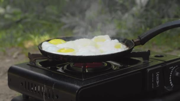 Яйца жарятся на сковороде в походе по газовой плите в природе.. — стоковое видео