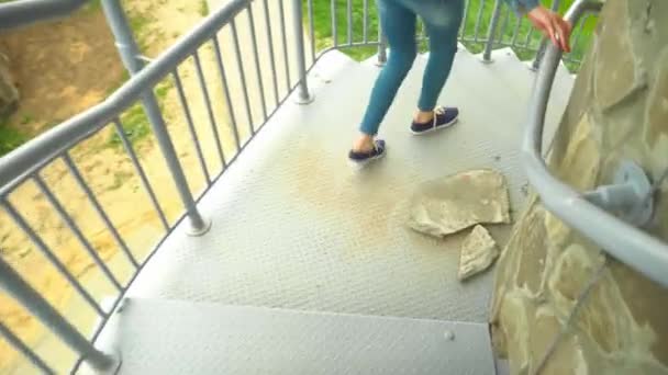 Una mujer camina por una escalera de caracol en jeans, un teléfono móvil en su bolsillo, — Vídeos de Stock