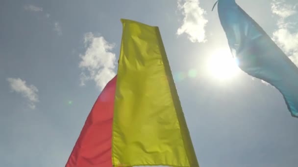 Kolorowe flagi wakacyjne trzepoczą na wietrze przed błękitnym niebem, — Wideo stockowe