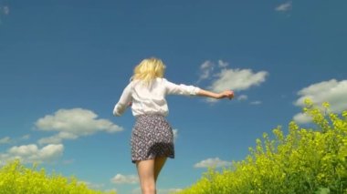 Genç bir kadın çiçek açan bir ırz tohumunun arasında koşuyor..